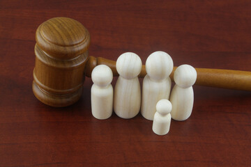 Family law concept. Judge gavel with many wooden figures of family members close-up.	