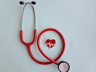 Stethoscope and red heart on light background