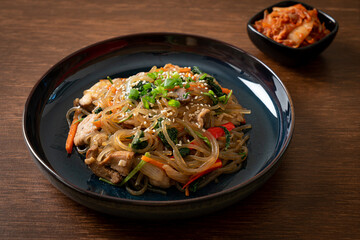 japchae or stir-fried Korean vermicelli noodles with vegetables and pork topped with white sesame - obrazy, fototapety, plakaty