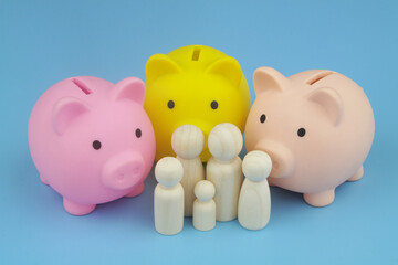 Family savings and family budget concept. Three piggy banks and family people figures on blue background.
