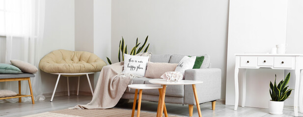 Interior of light living room with sofa and tables