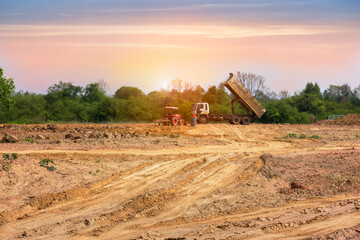 Fototapeta premium A truck is moving into sand at a ground leveling construction site., land plot for housing construction project with car tire print in rural area Land for sales landscape concept.