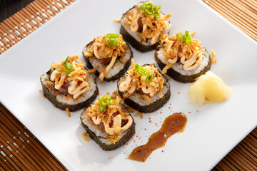 Japanese food and crispy onions served in restaurant on white plate on wooden table
