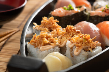 Japanese food and crispy onions served in restaurant on black boat on wooden table
