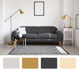 Comfortable sofa, table and modern lamp near white wall in living room. Different color patterns