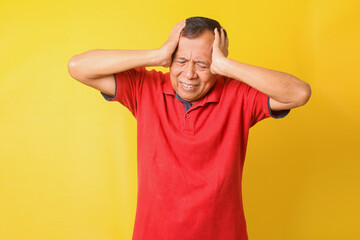 Fototapeta na wymiar Asian senior man wearing casual t-shirt over yellow background suffering from headache desperate and stressed because pain and migraine. Hands on head.