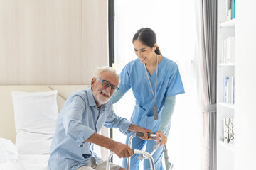Female nurse caring senior man using walker in rehab center. Caregiver helping caucasian elderly...