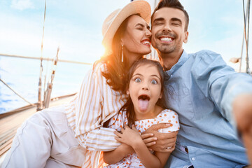 Happy young family resting on yacht - obrazy, fototapety, plakaty