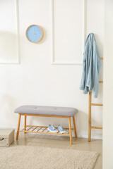 Fototapeta na wymiar Comfortable soft bench with shoes and ladder near white wall