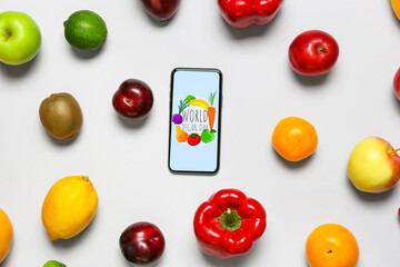 Fresh fruits, vegetables and mobile phone with text WORLD VEGAN DAY on grey background