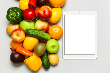 Different fruits, vegetables and tablet computer on grey background. World Vegan Day concept