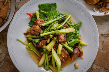 Stir fried kale vegetables with fried pork in the plate for breakfast or lunch or dinner,some menu on food table