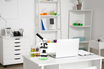 Modern workplace, microscope, chemical glassware and laptop in medical laboratory