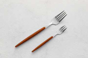 Stylish stainless steel forks on light background