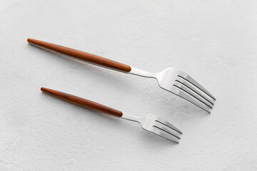 Stylish stainless steel forks on light background