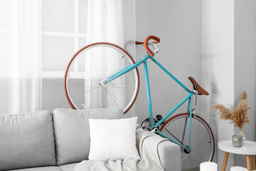 Interior of light living room with bicycle and grey sofa