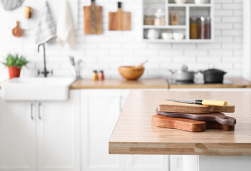 Stack of cutting boards and knife on wooden table in kitchen