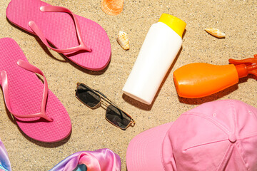 Fototapeta na wymiar Bottles of sunscreen cream with beach accessories and seashells on sand