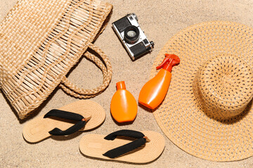 Bottles of sunscreen cream with beach accessories and photo camera on sand