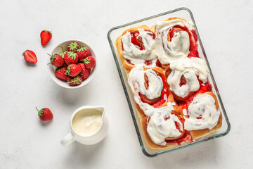 Baking dish with strawberry cinnamon rolls and cream on white background