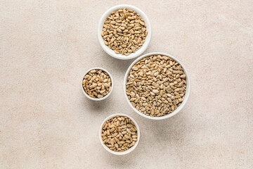 Bowls with peeled sunflower seeds on white background