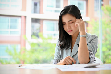 Obraz premium Young Asian businesswoman concentrated reading a business document report.