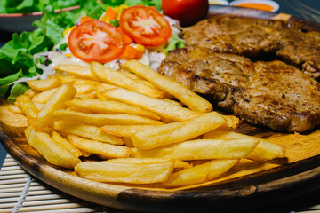 Grilled steak and lettuce, French fries on wooden plate