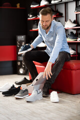 Millennial man choosing sports footwear in outlet