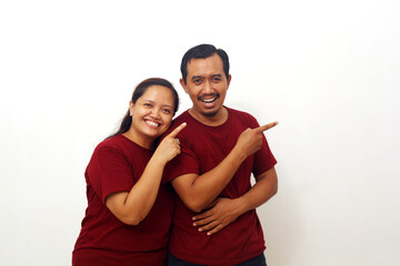 Fototapeta premium Happy Asian couple standing while pointing beside them. Isolated on white with copyspace
