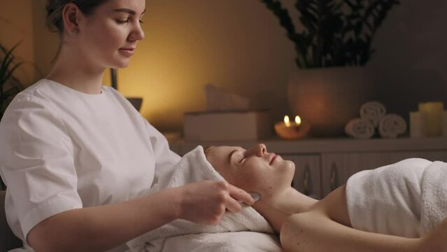 Woman during a massage on the neckline with professional tools at these salon. Dermatology skin care facial therapy. Medical spa anto wrinkles procedure. Woman