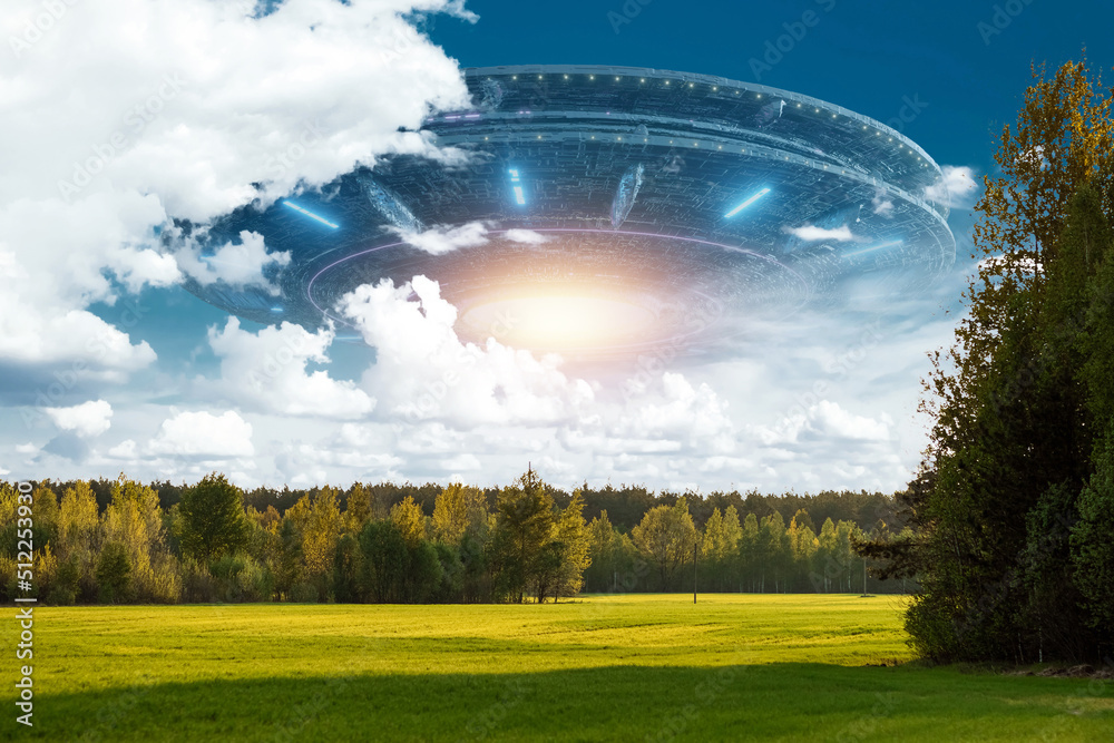 Wall mural ufo, an alien saucer hovering above the field in the clouds, hovering motionless in the sky. unident