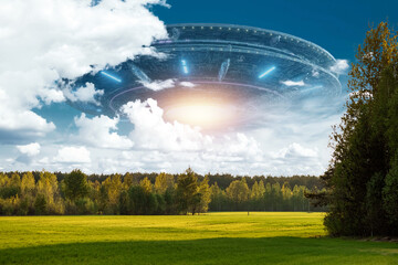 UFO, an alien saucer hovering above the field in the clouds, hovering motionless in the sky....