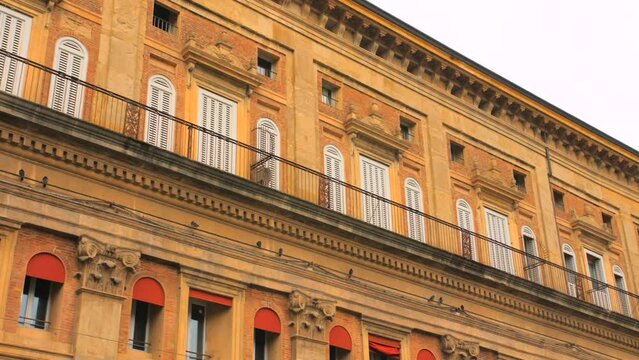 Low angle shot of ancient mullioned windows of the Palazzo Accursio, town hall in downtown of Bologna in Italy on a cloudy day.