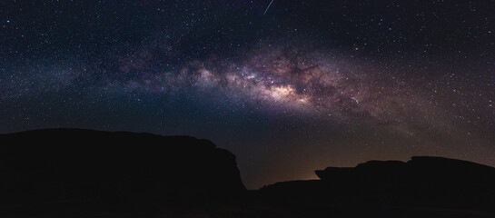 Milky way in the night sky and stars on dark background with noise and shadows of mountains. Photo...