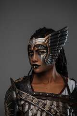 Portrait of isolated on grey martial african woman warrior dressed in beautiful steel armor.