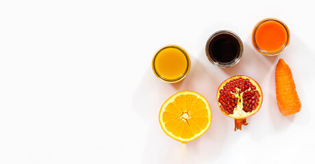 three kinds of juices orange, pomegranate, carrot on a white surface, carrot and orange slices, pomegranate seeds, top view, healthy food concept, vitamin detox, diet