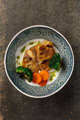 Overhead view of grilled fish fillet served with vegetables