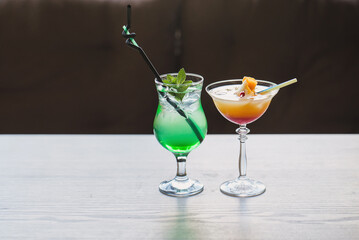 two refreshing cocktails on a wooden table. Green mojito with lime and ice. Summer delicious cocktails appetizers