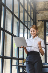 Overjoyed asian business woman worker using laptop working at desk in office in the day, feeling happy.