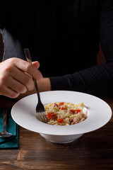 Person eating pasta in restaurant. No face