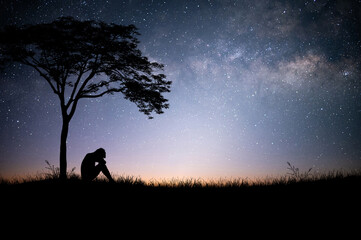 The young man sat down alone under a large tree above a mountain meadow with beautiful night sky, star and Milky Way. He was tired, sad and disappointed.