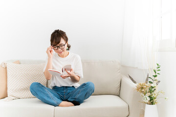 読書中に眼鏡を直すおしゃれな日本人女性（メガネ）
