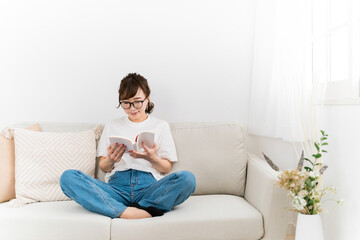 Obraz premium 家のソファで読書するおしゃれな日本人女性（本・漫画・小説） 