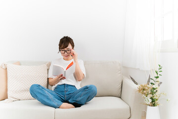 Obraz premium 読書中に眼鏡を直すおしゃれな日本人女性（メガネ） 