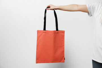 Female hand holding eco or reusable shopping bag against white background