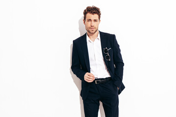 Portrait of handsome confident stylish hipster lambersexual model. Sexy modern man dressed in black elegant suit. Fashion male posing in studio in sunglasses. Isolated