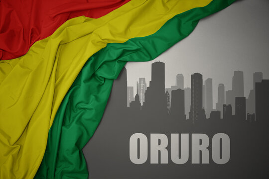 abstract silhouette of the city with text Oruro near waving national flag of bolivia on a gray background.