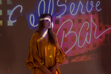 silhouette of a young beautiful woman on the background of neon projector inscriptions, slight blur