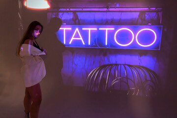 silhouette of a young beautiful woman on the background of neon projector inscriptions, slight blur