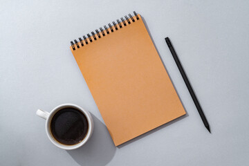 Cup of coffee with notebook on gray background top view
